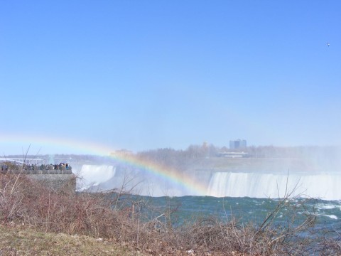 Visitors at Table Rock, Niagara Falls, Canada standing under a rainbow