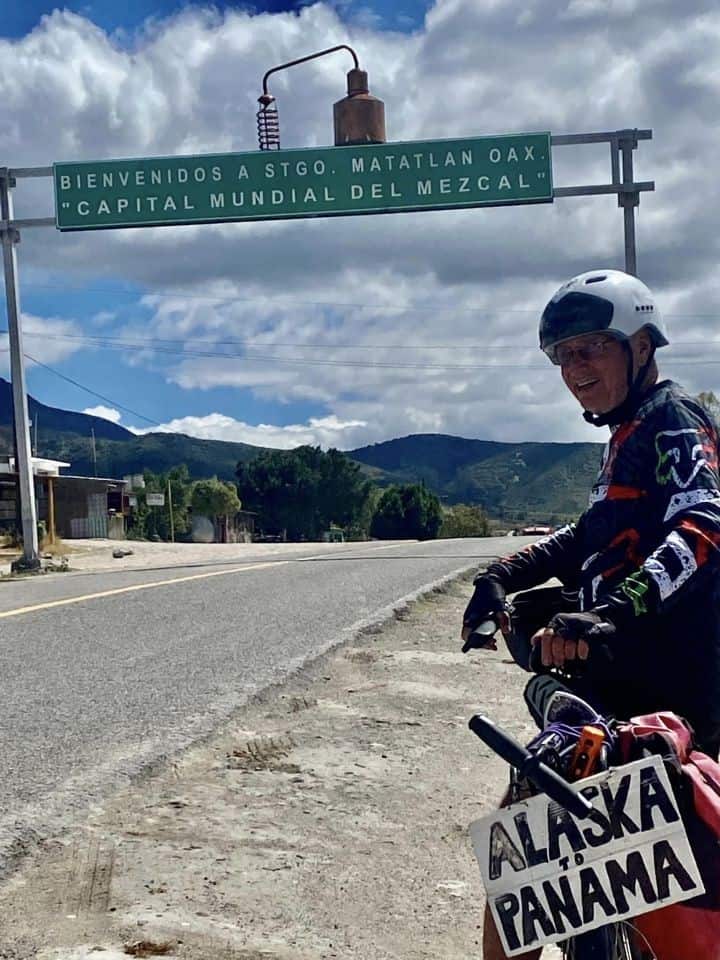 Robert Fletcher rides under the welcome sign for Santiago Matatlán, Mexico.