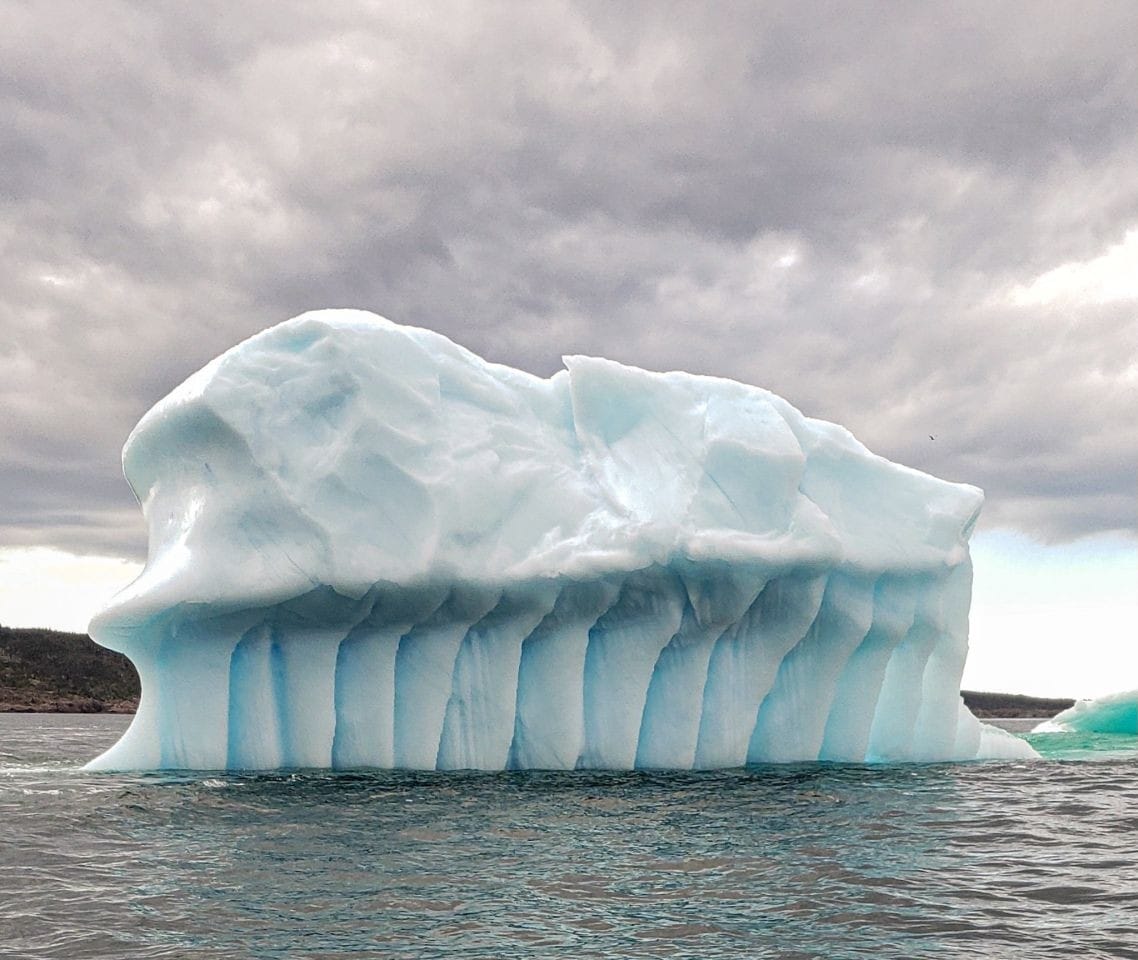 An iceberg chiseled, carved and eroding by the ocean grounded in Conception Bay Newfoundland and Labrador Canada.