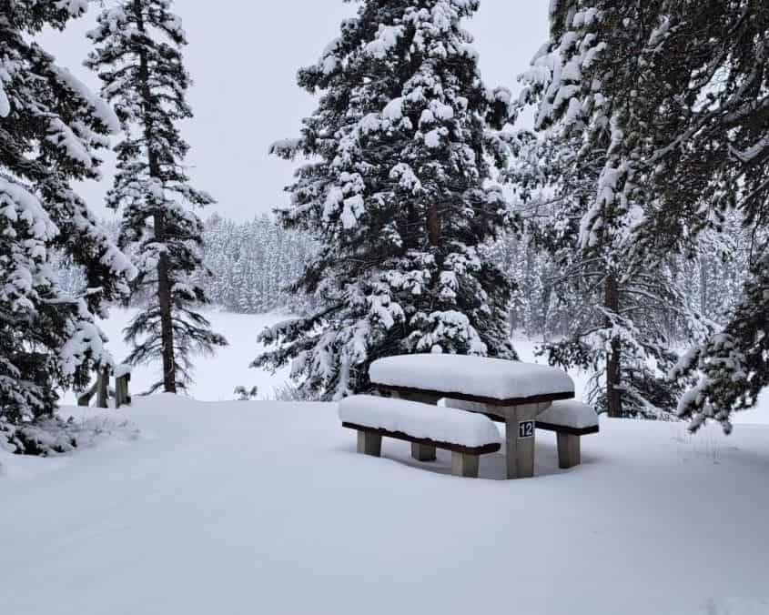 Snow covers a picnic table in the winter at the Johnson lake Day Use Area in Banff, Alberta, Canada.