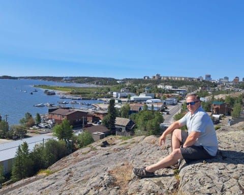 An adventure seeker sits on the rocks and enjoys the views duringa hot summer's day atop the Bush Pilot's Monument in Yellowknife