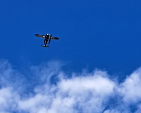 A float plane flies  above the clouds and across a deep blue summer sky in Yellowknife Northwest Territories.