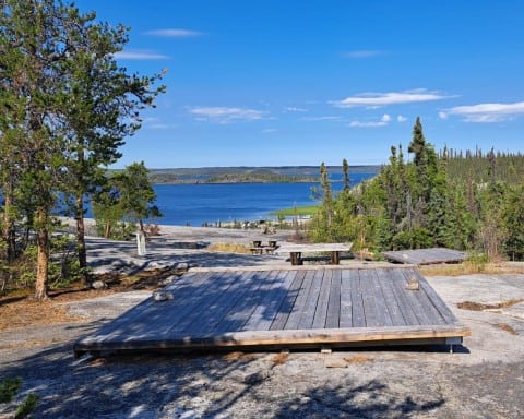 Perched high on a hill wooden tent pads are constructed over the Canadian Shield in the Northwest Territories giving these walk in tenting sites incredible views of Prelude Lake below.