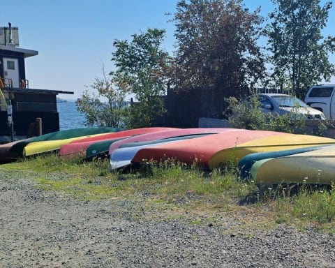 Yellowknife Northwest Territories Travel Guide shows a line of colourful canoes on the shores of Great Slave Lake in Canada.