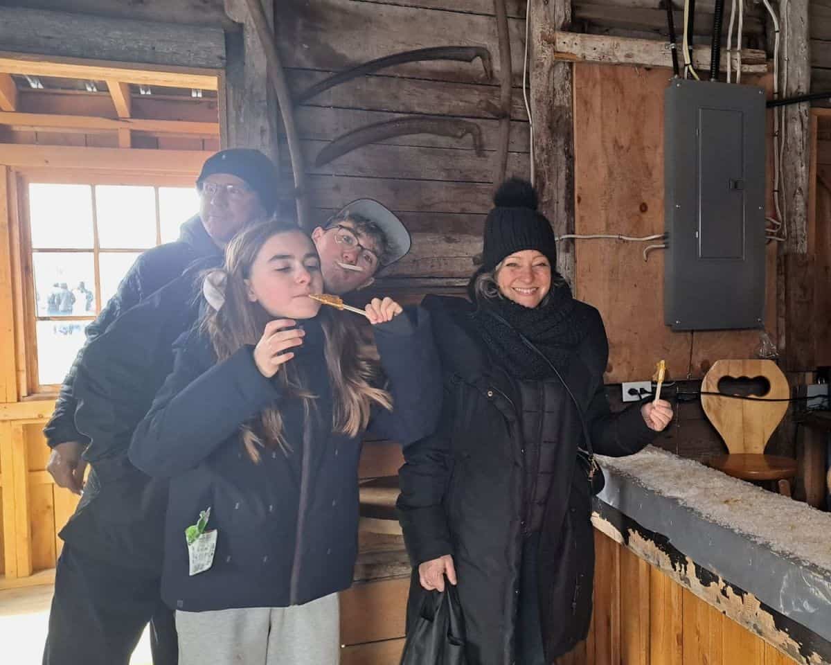 A family is all smiles at they enjoy their maple taffy or Tire sur la neige in French while they visit a maple syrup sugar shack (Cabanes a sucre) south on Montreal in the early spring in Quebec.