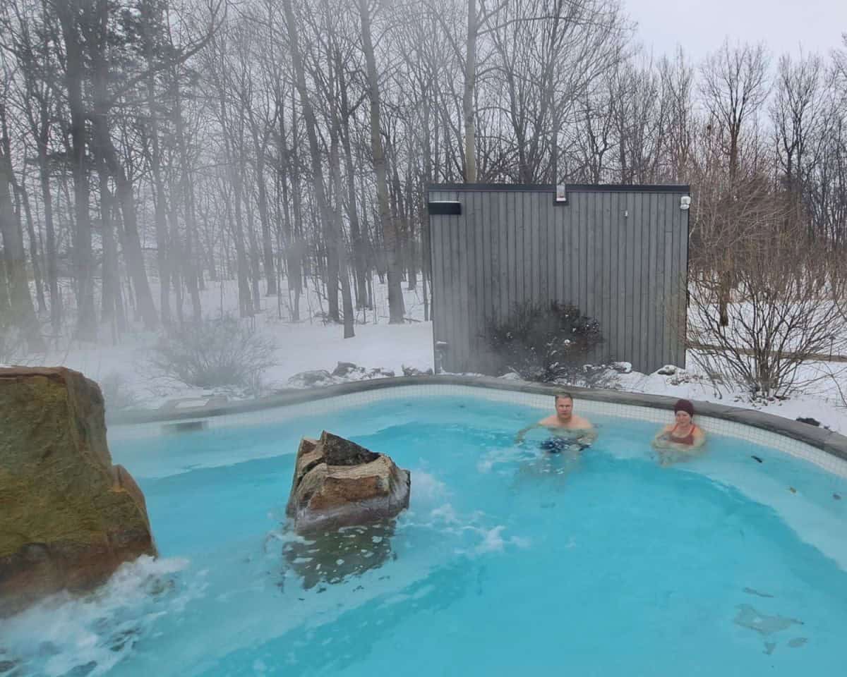 Two people enjoy an outdoor hot pool during the early spring on a snowy early spring day in Mont Saint-Hilaire south of Montreal