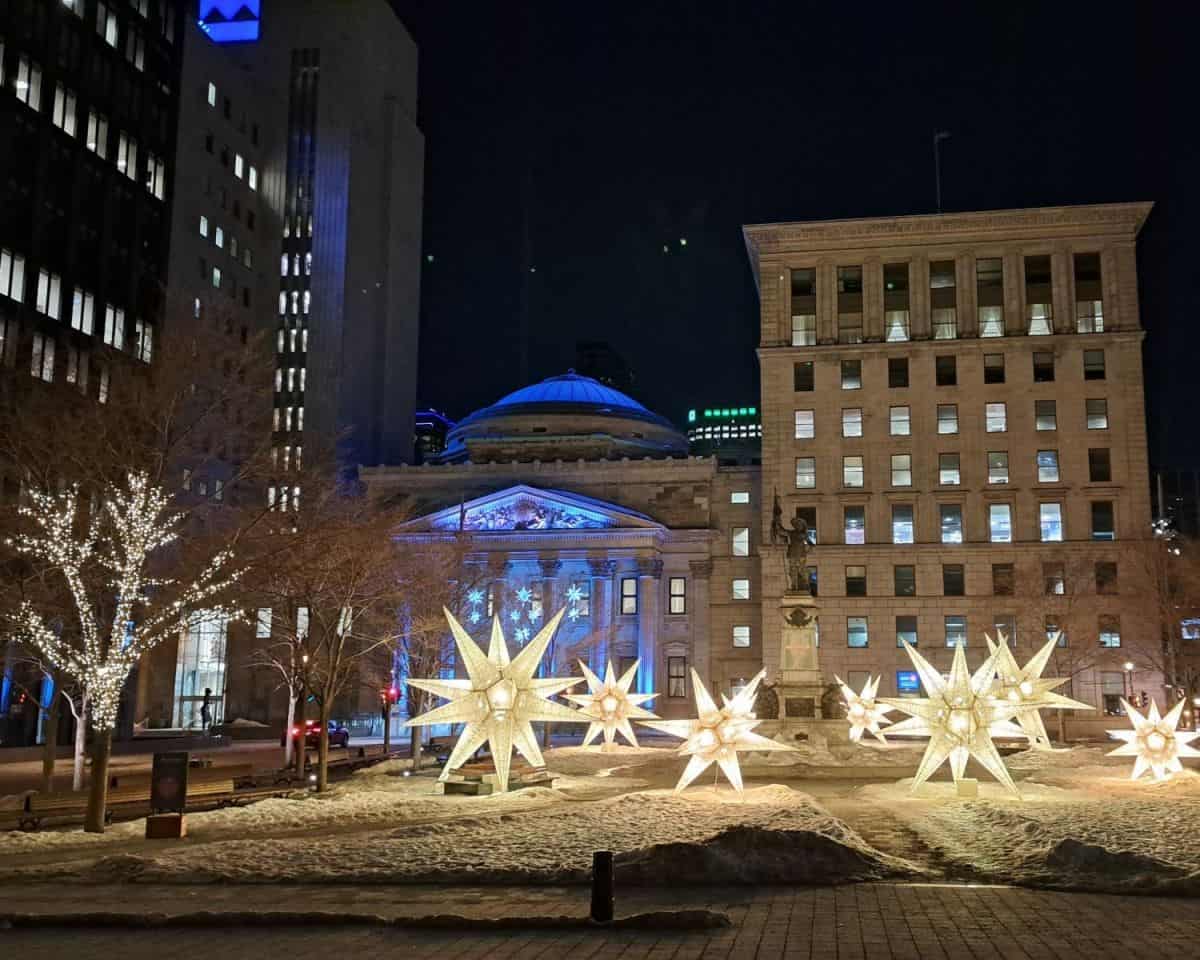 A park in Old Montreal is lit up with giant 3 dimensional stars and lights on trees throughout the winter nights in Montreal QC Canada.