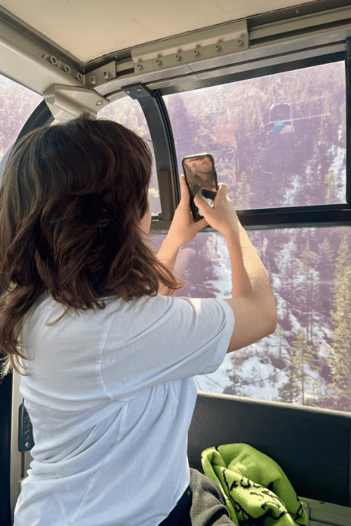 A woman takes a video while travelling up the Sulphur Mountain Gondola, Banff, Alberta.