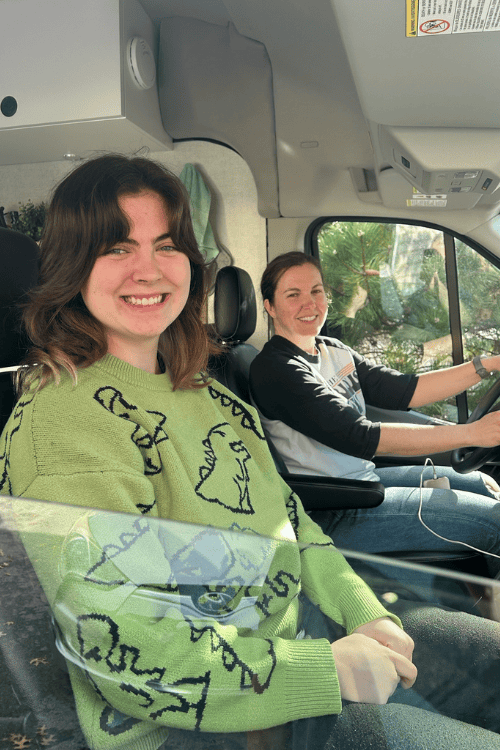 Two woman inside a camper van, smiling.