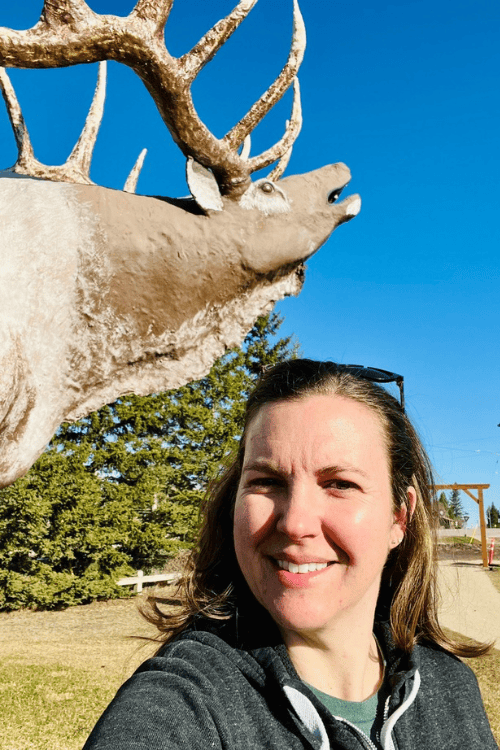 Woman poses with the Onanole Elk statue, Manitoba.