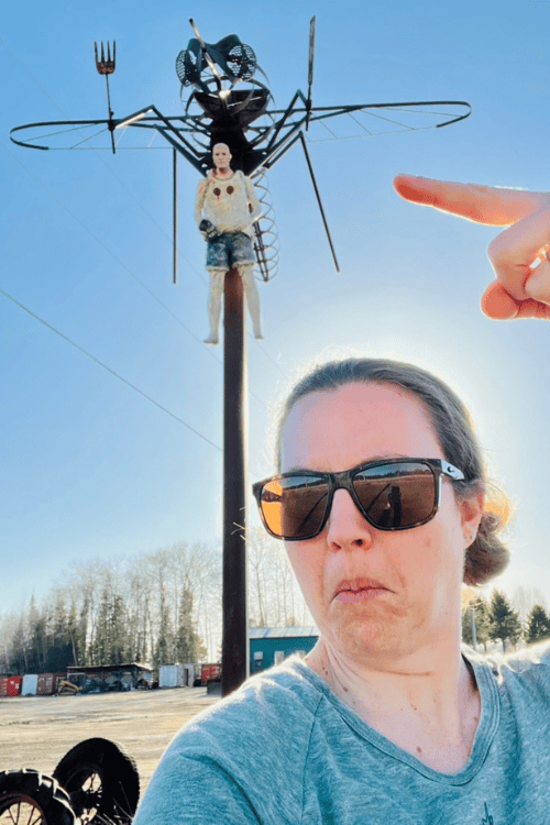 A woman poses with Mosquito carrying a man art in Upsala, Ontario