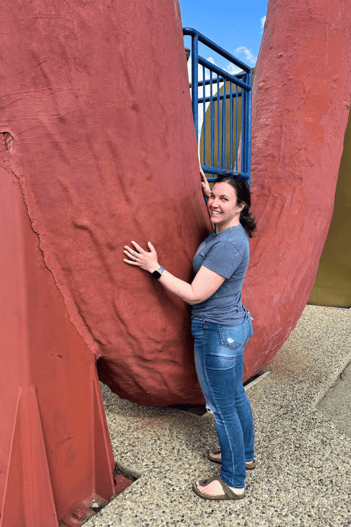A woman stands next to the World's Largest Sausage, Mundare, Alberta