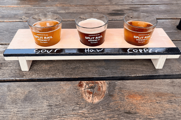 Three small glasses of beer in a wooden board, representing a flight, from Split Rail Brewing Co in Gore Bay, Manitoulin Island, Ontario