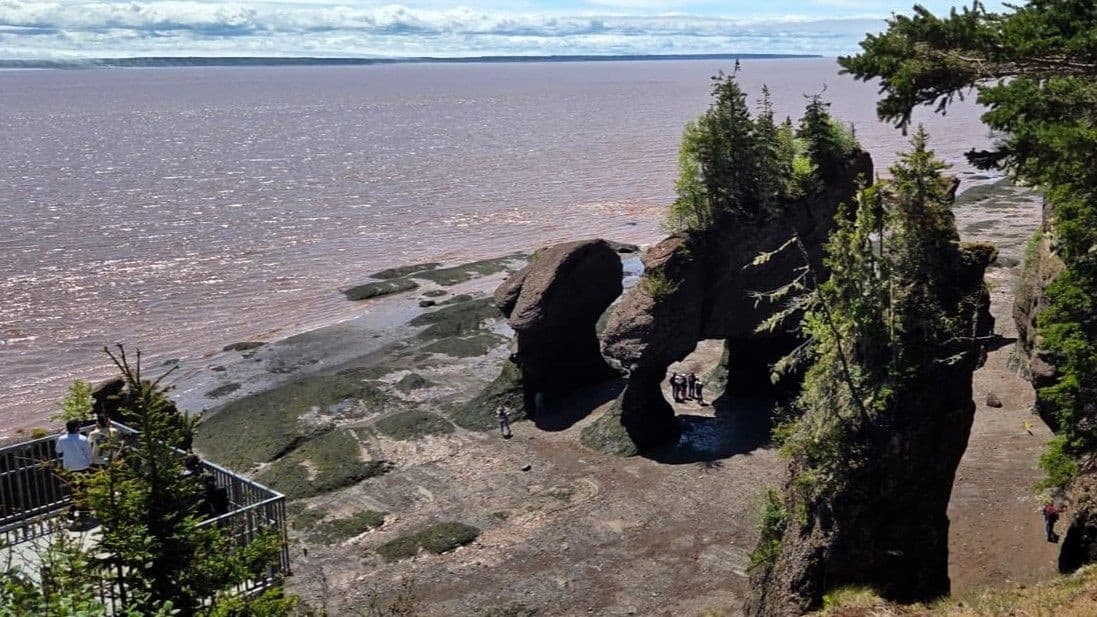 Clearing skies over the Bay of Fundy viewed from the platform at Hopewell Rocks Provincial Park, showing the exposed ocean floor at low tide.