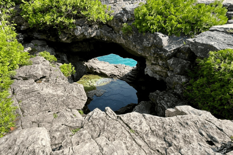 Grey rock formation providing a glimpse into the aqua-blue waters of Georgian Bay.