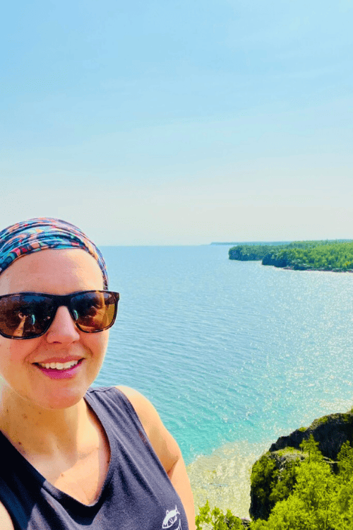 A woman smiles from a look-out over the aqua-blue waters of Georgian Bay
