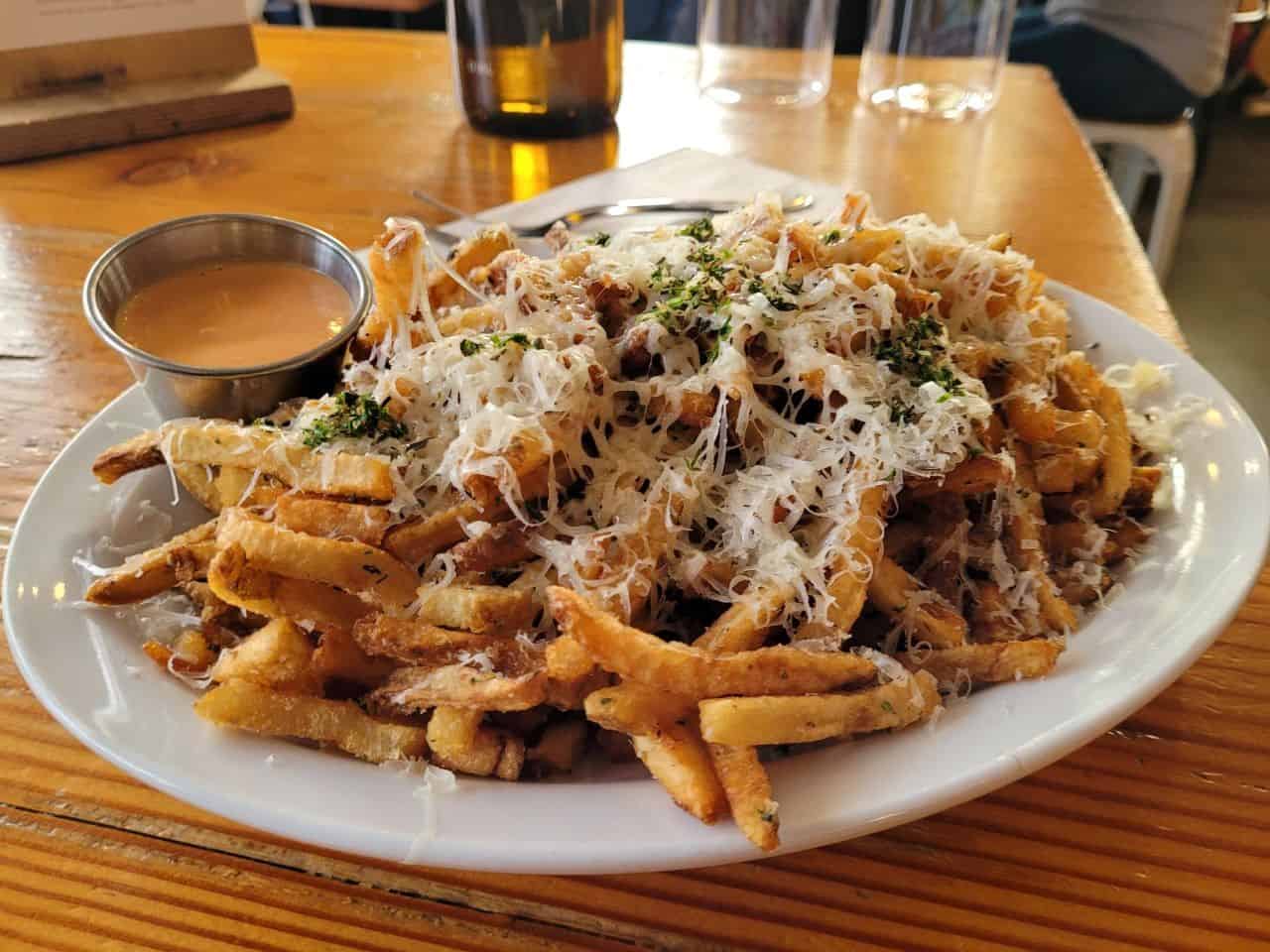 A plate of perfectly crispy fries, seasoned with fresh herbs, garlic, and melted Gruyère. The ultimate savoury side to pair with any craft beer at Bannerman Brewing Co., St. John's, NL.