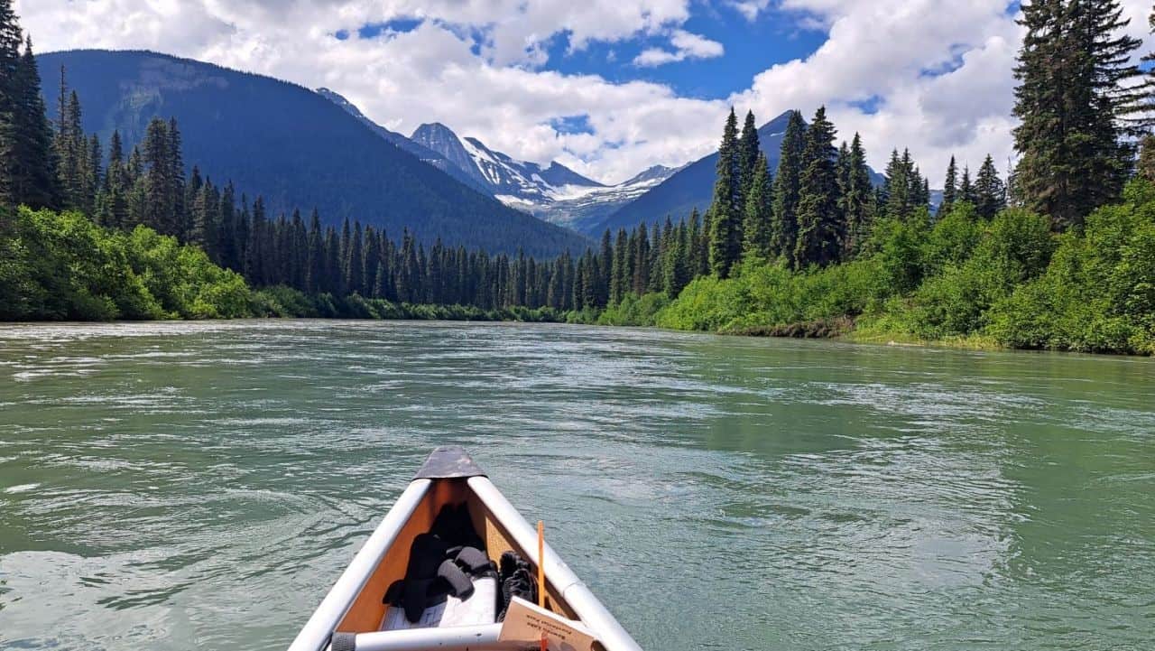 The tip of the canoe points the way down the Cariboo River, a fast moving section of water with frequent sweepers and downfall to watch for on the Bowron Lakes Canoe Circuit in British Columbia