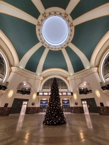 A decorated Christmas tree glows inside Winnipeg Union Station, adding warmth and seasonal charm to a winter rail stop along VIA Rail’s The Canadian journey across snow-covered Canada.