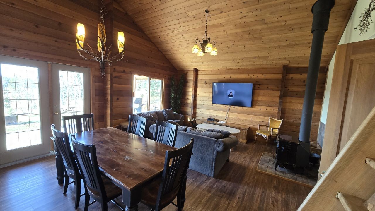 A cozy cabin interior at Bearberry Cabins near Sundre, Alberta, Canada, featuring a wood stove, dining area, and comfortable living space.