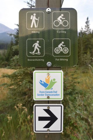 A Trans Canada Trail sign indicating route access and direction. While the trail spans Canada, cycling conditions vary by region, and not all sections are fully connected for continuous riding.
