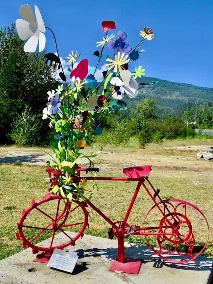 Metal sculpture of a red bicycle with a large bouquet of metal flowers in basket.